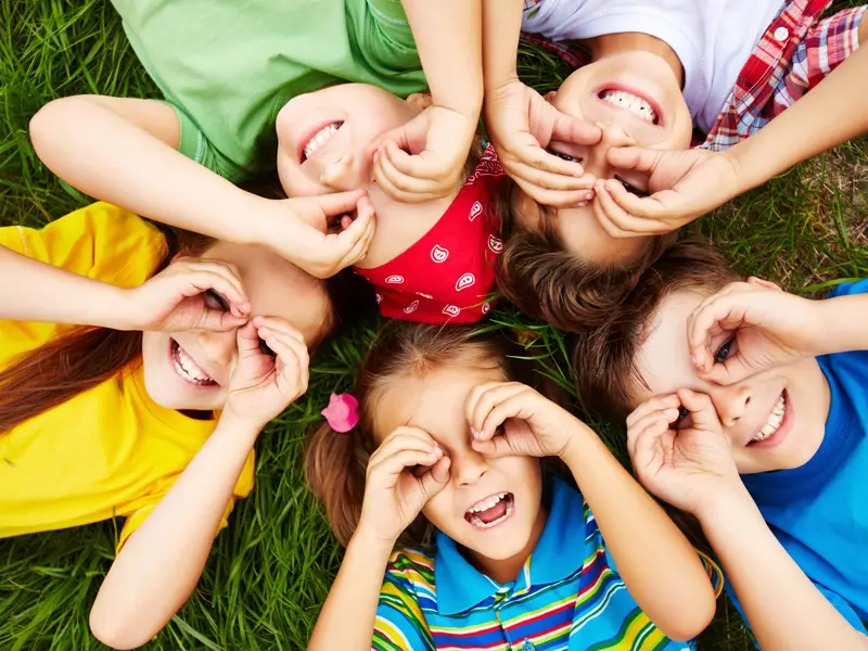 Kinder liegen auf dem Rasen und schauen in den Himmel